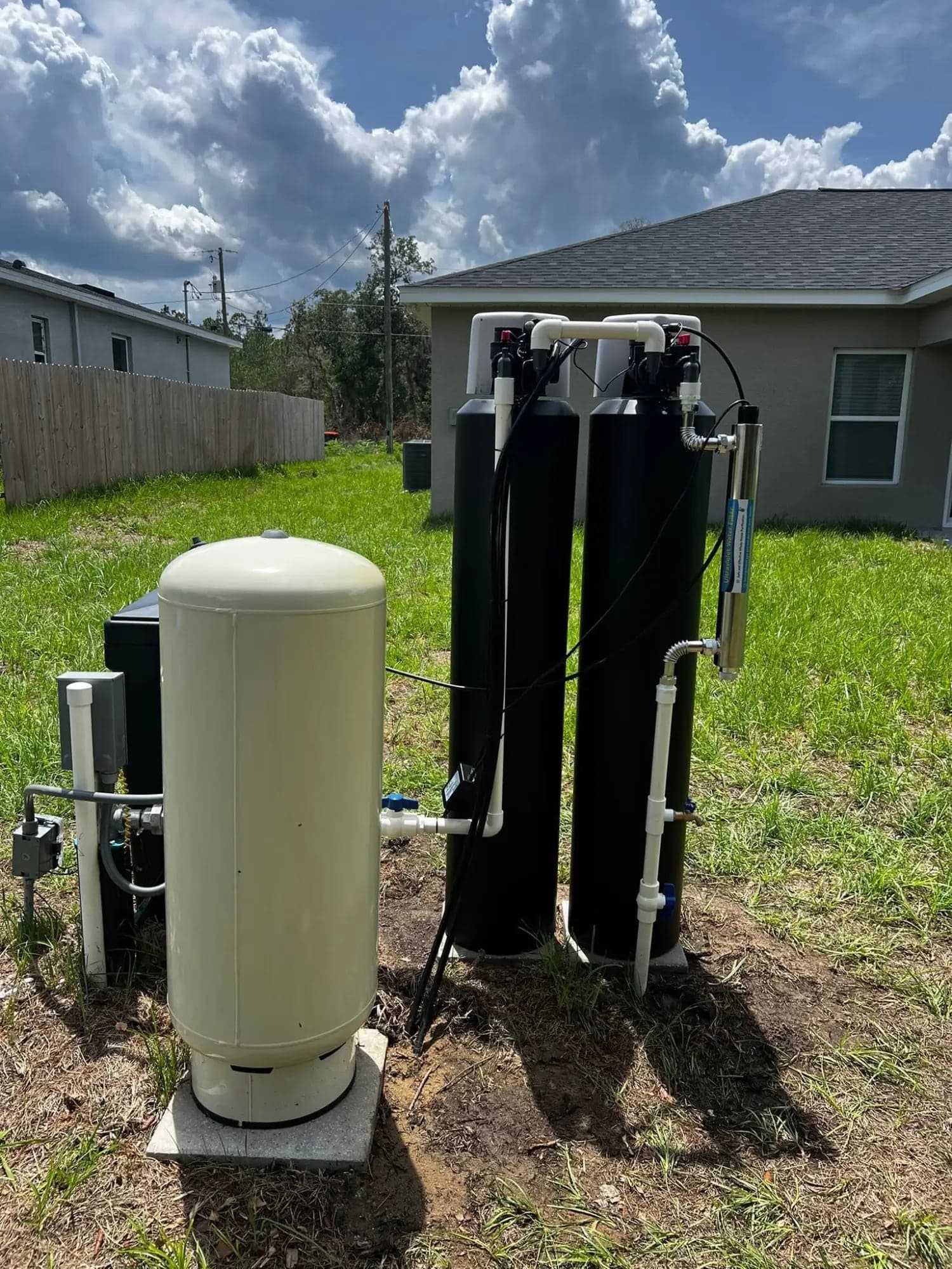Whole-house water filtration system with UV purifier and pressure tank installed in a backyard
