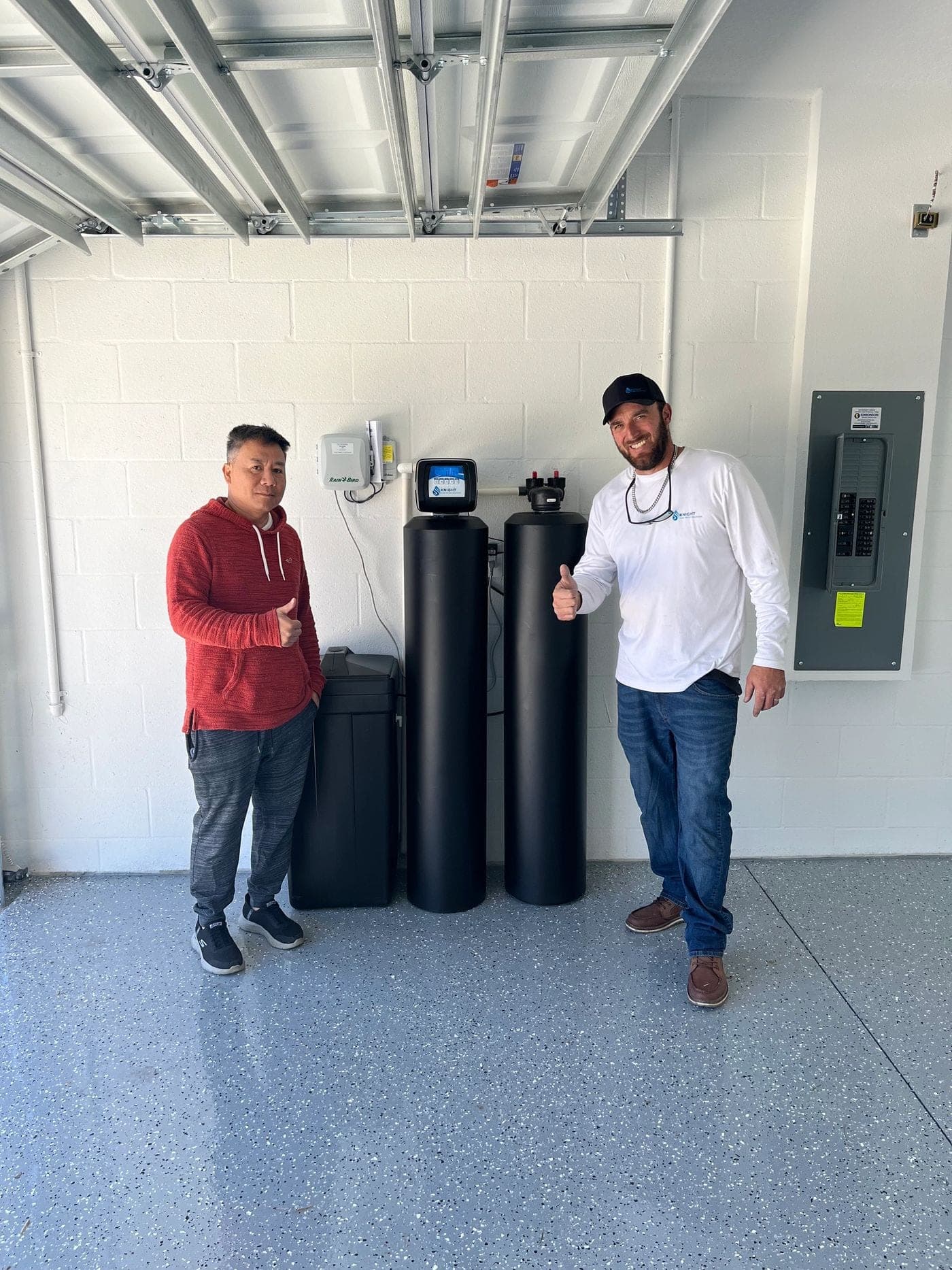 Knight Home Water Solutions technician and customer beside a newly installed water softener system in a garage