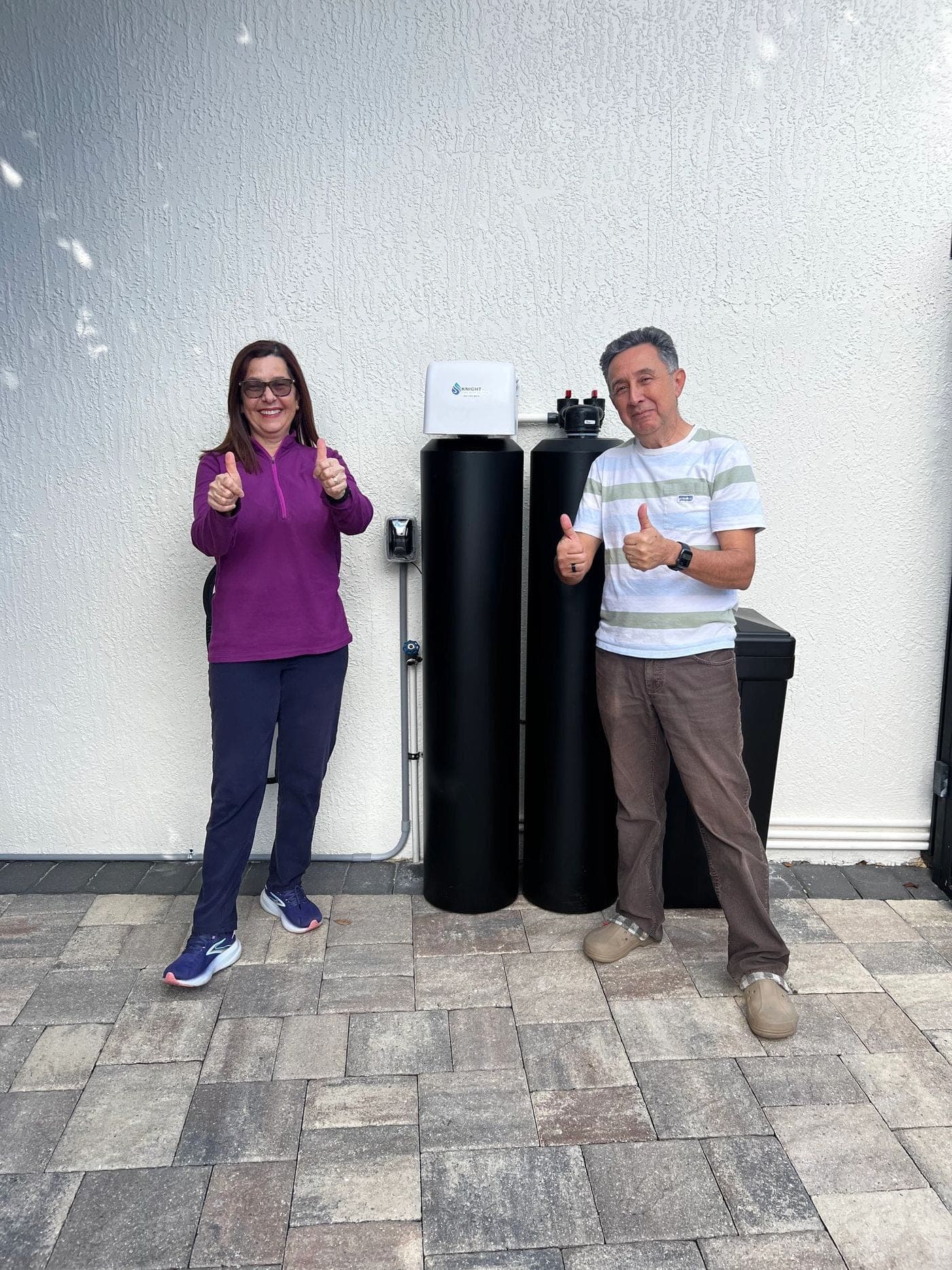 Customers giving a thumbs up next to their new Knight water softener tank