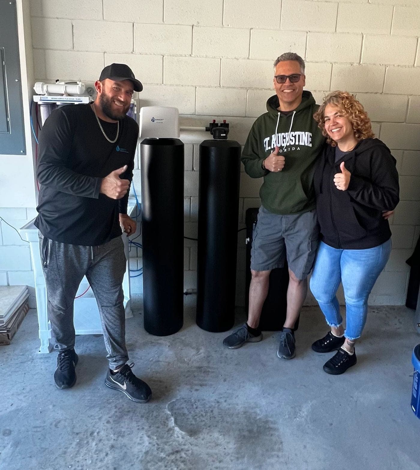Knight technician with happy customers beside a dual-tank water treatment system